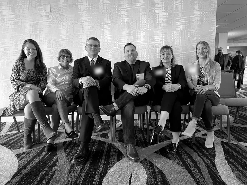 Craig Smith seated with a conference panel; other attendees’ name badges obscured