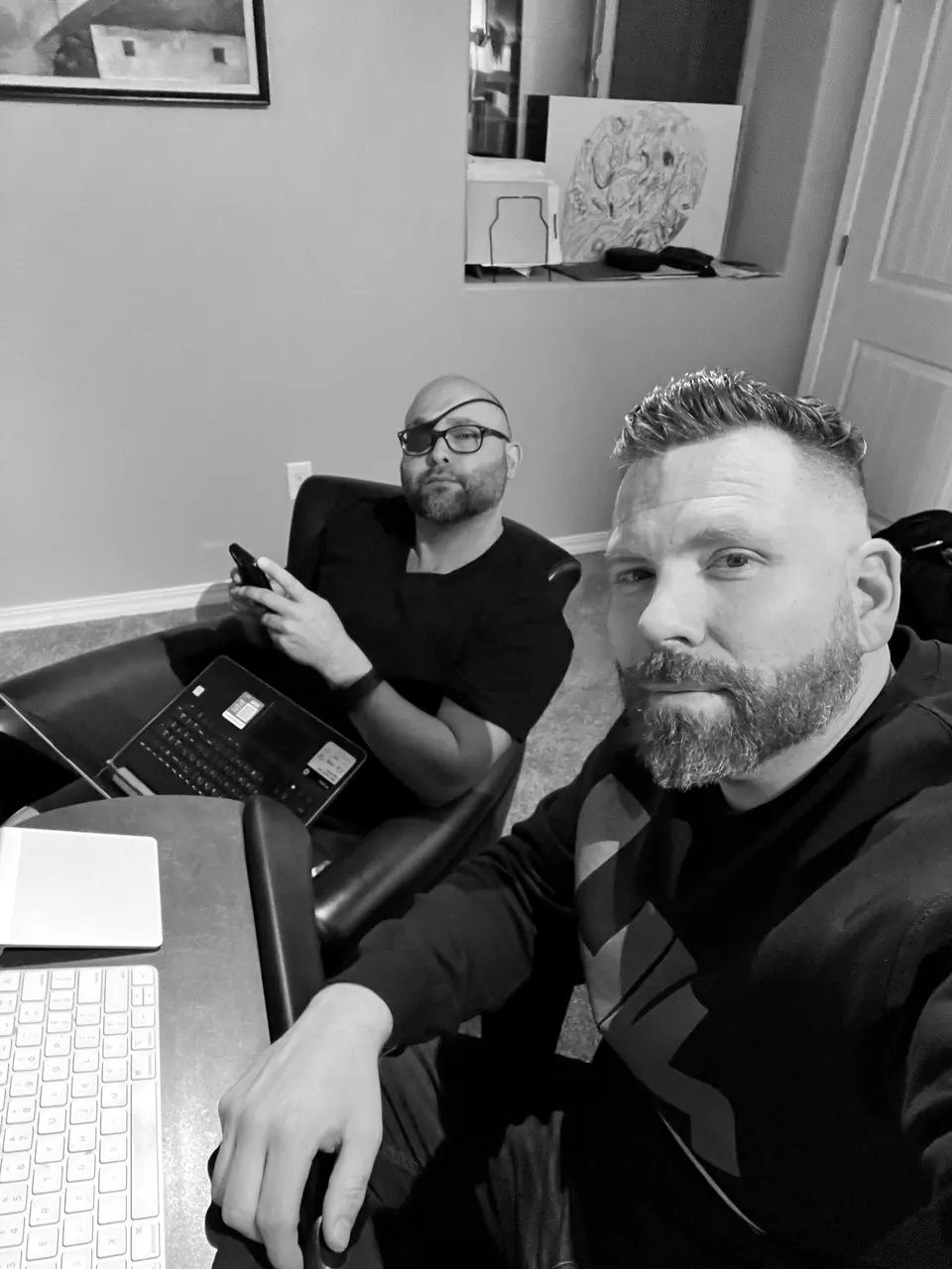 Craig Smith at a desk with a colleague working on a laptop behind him; colleague’s face obscured
