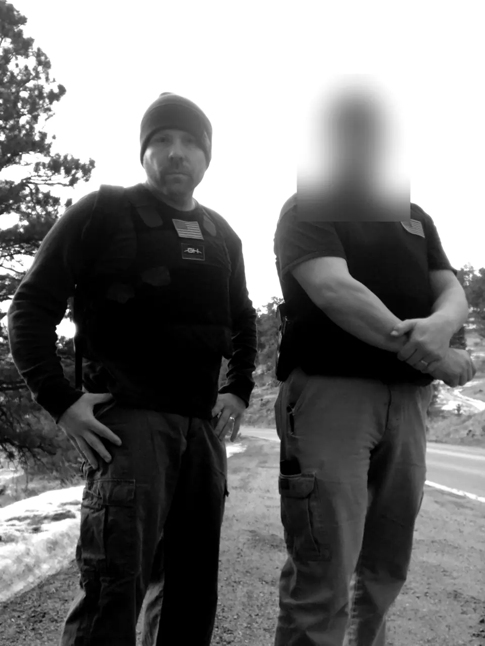 Craig Smith and a colleague in plate carriers on a mountain road; colleague’s face obscured