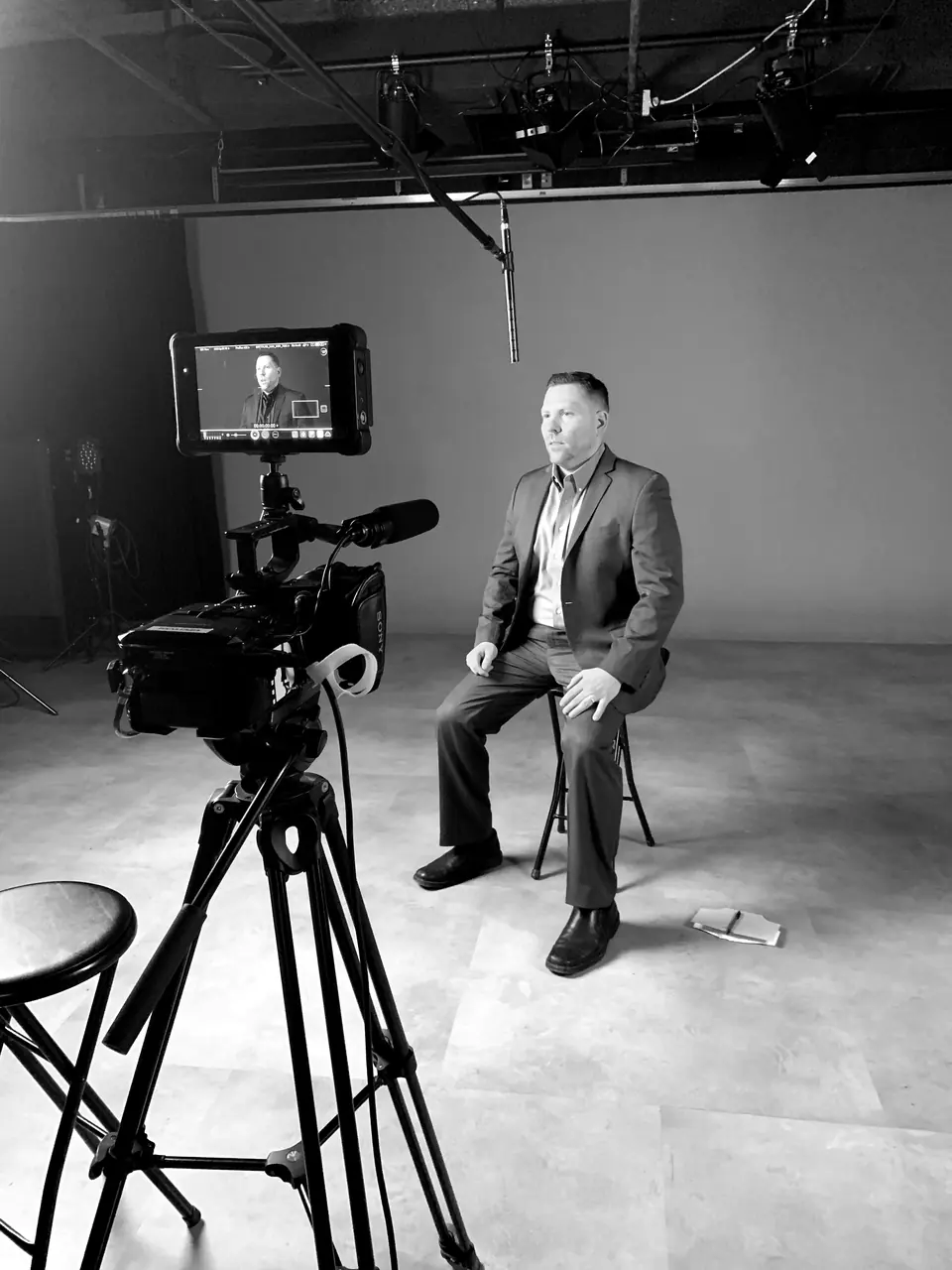Craig Smith seated in a studio facing a television camera, with his image on the camera monitor