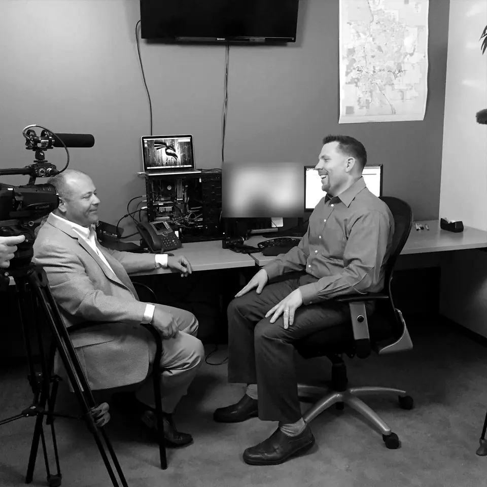 Craig Smith being interviewed for television in an office; screen content obscured